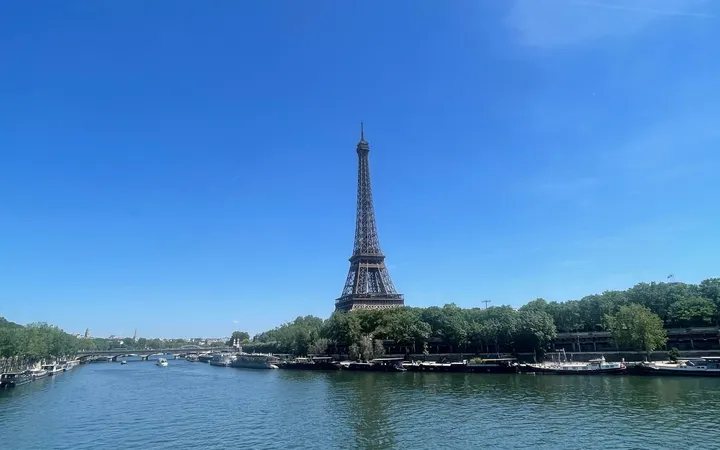 La tour Eiffel vue depuis la Seine, sous un ciel bleu